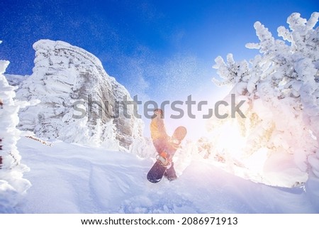 Snowboarder with snowboard background blue sky with sun light frozen rocks, Sheregesh ski resort. Concept extream freeride on fresh snow.