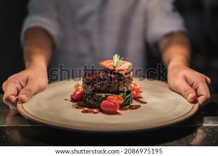 Chef serving oven-seared beef tenderloin steak with peppercorn sauce at the restaurant. Royalty-Free Stock Photo #2086975195