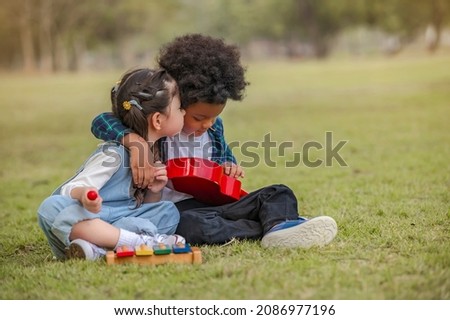 A little girl kisses a boy on the cheek. while he is shying