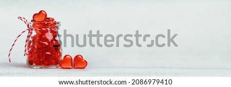 Two red glass hearts and a jar full of hearts. Love. St Valentines Day card. 14 February, wedding invitation or thank you concept. Wide banner with copy space