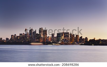 Australia Sydney city CBD panoramic view at sunset across sydney harbour waters blurred waves illuminated landmarks