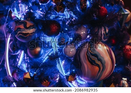 Creative blue Christmas tree decorated with hand painted Christmas ball and neon garland. Magic atmosphere and festive decorations