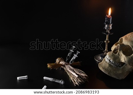 Voodoo doll and candles. Skull and syringes on a black background. People management concept. Compulsory vaccination. Drugs and Medicine. Ritual and conspiracy. Copy space.
