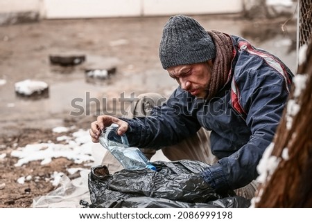 Poor homeless man with trash bag outdoors on winter day Royalty-Free Stock Photo #2086999198