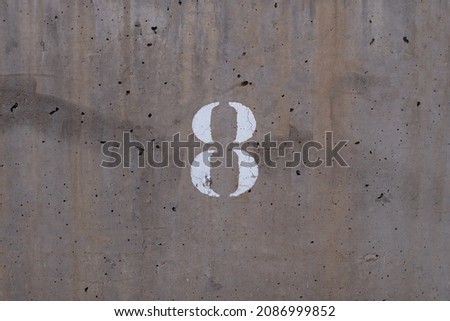 typography of the number eight imprinted on a cement wall, centered