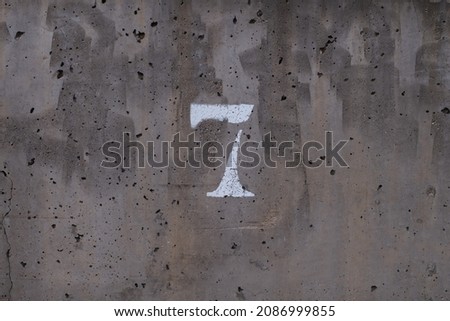good luck number stamped on a concrete wall. Number 7 centered, horizontal view