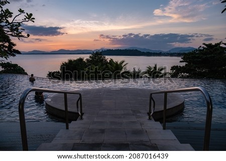 swimming pool on a luxury vacation in Thailand, pool looking out over the bay watching sunset. Infinity pool over ocean
