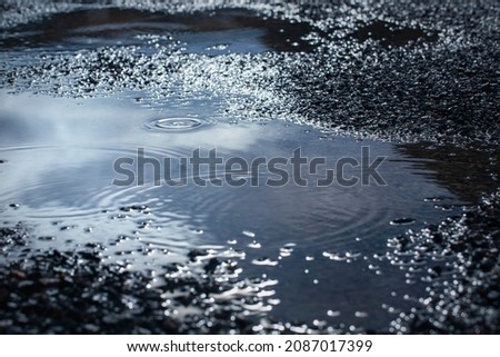 water puddles with water on cracked wet asphalt road after hard rain fall,rainy season background. Royalty-Free Stock Photo #2087017399