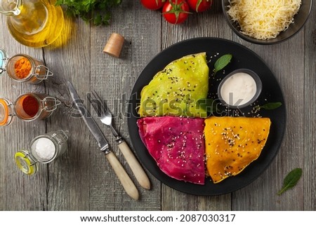 Colorful pancakes with chicken and lb vegan stuffing. Naturally colored with juice or seasoning. Served with sauce or yoghurt. Wooden background.