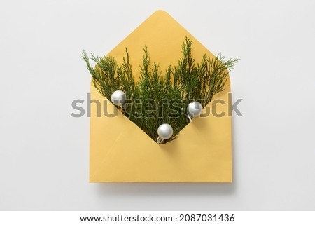 Envelope with coniferous branches and Christmas balls on white background