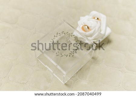 Wedding gold wedding rings in a transparent box, close-up, on a wooden background, selective focus. Wedding invitations on the floor	
