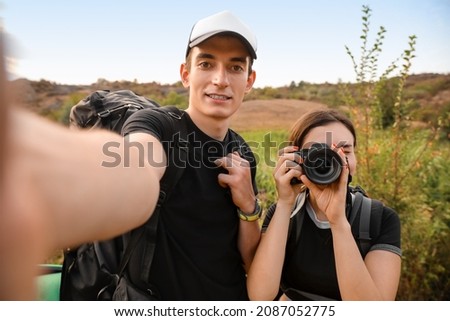 Couple of young tourists taking selfie in countryside