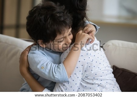 Adorable little kid son cuddling affectionate loving young Indian mother, missing after long separation. Happy two generations family showing tender feelings at home, family relations. Royalty-Free Stock Photo #2087053402