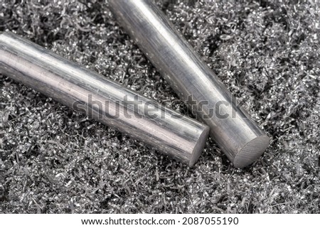 Two aluminum billets on shavings from miling machine. Industrial closeup photo. Side view photo of two metal rods on swirly aluminum shavings.  Royalty-Free Stock Photo #2087055190