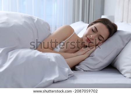 Young woman sleeping in comfortable bed with silky linens Royalty-Free Stock Photo #2087059702