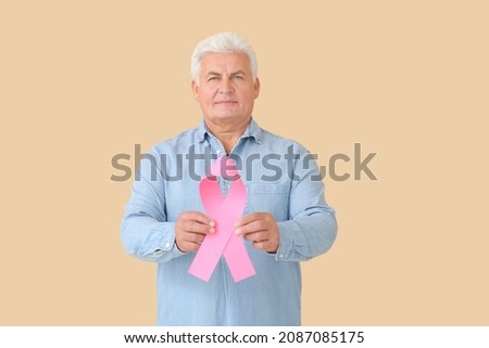 Mature man with pink ribbon on color background. Breast cancer awareness concept