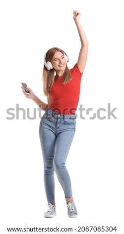 Young woman with mobile phone and headphones dancing on white background