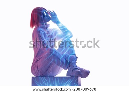 Double exposure of woman and futuristic holographic interface to display data. Female in futuristic costume using VR helmet. Augmented reality, future technology, game concept. White background.