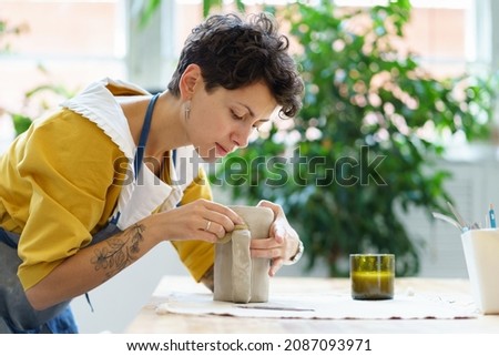 Professional sculptor girl creating ceramic tableware in studio. Young woman artist work with wet clay jug shaping handmade dishes. Creative craftswoman in workshop space. Pottery art hobby concept