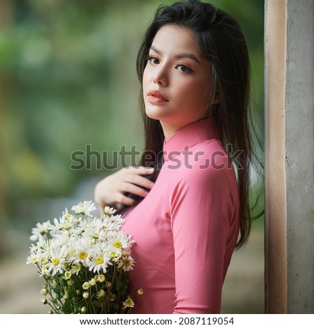Ho Chi Minh City, Vietnam: Charming Vietnamese woman in ao dai, taking pictures with chrysanthemums