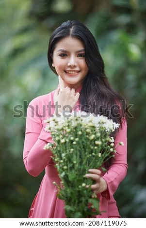 Ho Chi Minh City, Vietnam: Charming Vietnamese woman in ao dai, taking pictures with chrysanthemums Royalty-Free Stock Photo #2087119075