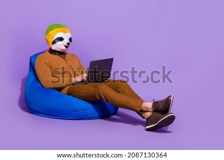 Full size profile photo of sloth head person sitting soft bag use netbook isolated on purple color background