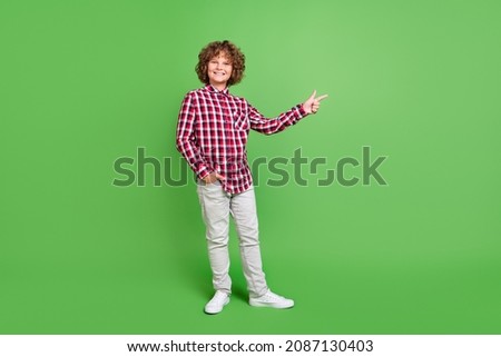 Full length body size view of attractive cheerful guy demonstrating copy space isolated over bright green color background