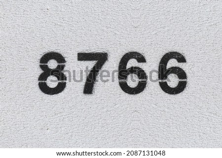 Black Number 8766 on the white wall. Spray paint. Number eight thousand seven hundred sixty-six.