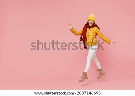 Full size body length jubilant young woman 20s years old wear yellow jacket hat mittens look camera jump move go keep mouth open hurry up isolated on plain pastel light pink background studio portrait Royalty-Free Stock Photo #2087146693
