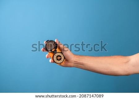 compass in the hand of a traveler, searching for yourself on the way, a concept. Magnetic compass in a man's hand, photo on a blue background