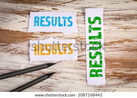 Results, Business concept. Torn sheets of paper on a white wooden background.