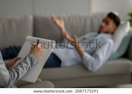 Psychological trauma. Psychologist working with depressed arab man at office, middle eastern male patient lying on couch while having session with therapist