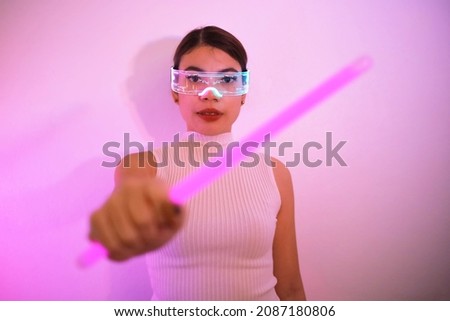 Beautiful Asian woman  with VR glasses, playing with blue and pink light. The concept of cyber game and the future