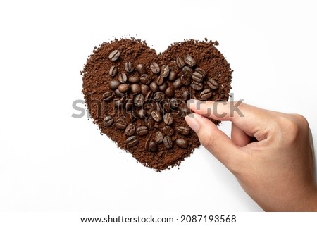 Coffee beans in the shape of a heart with woman hand creative concept on white background. valentine concept