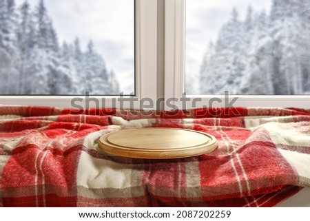 Wooden pedestal on window sill and winter landscape of forest. Free space for your decoration. 