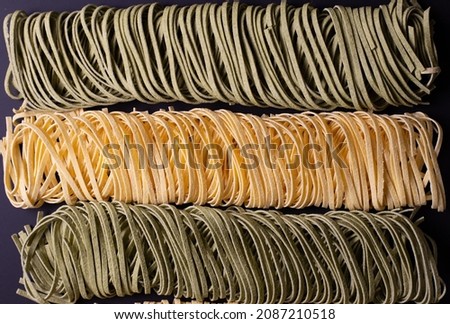 Tagliolini in two colors. Dry pasta on a dark background. 
