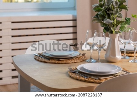 Breakfast setup on wooden table with nice vase and modern chair. A table set for forur people family.