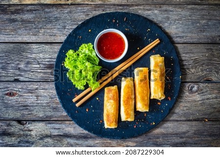 Spring rolls on stone plate on wooden table Royalty-Free Stock Photo #2087229304