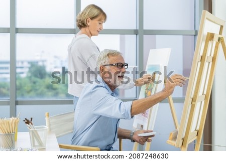 Happy older husband, wife senior couple elderly family, caucasian mature, adult and retirement having pleasure together and painting picture on canvas at home. Freetime, relaxed lifestyle of people.
