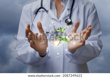 Laboratory assistant shows sprout with earth and alternative energy on blurry background.