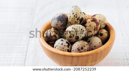 Quail eggs in metal plate on white wooden old background. Selective focus.