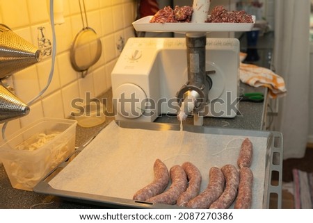 Homemade sausages on a tray, meat grinder in the background, picture from vasternorrland sweden.