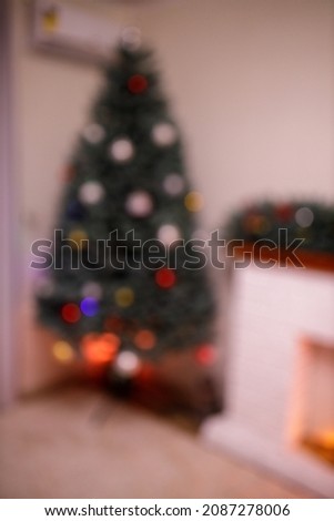 New Year tree and home decorated in the evening. Gift boxes and red socks with present near white brick fireplace. Concept - Upcoming 2022 New Year. Calm and peaceful atmosphere. Intentionally blurred