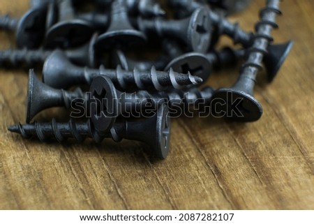 Black screws. Close-up of the self-tapping screws on a wooden background