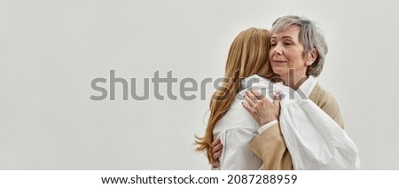 Loving old grey-haired mother hug support adult daughter, isolated on whites studio background. Caring supportive mature mom embrace comfort caress grownup child. Copy space, banner. Royalty-Free Stock Photo #2087288959