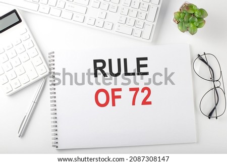 Office desk table with keyboard, notepad and calculator. Top view ,text RULE OF 72 Royalty-Free Stock Photo #2087308147