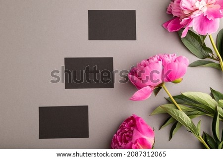 Black business card with pink peony flowers on gray pastel background. top view, flat lay, copy space, still life. Breakfast, morning, spring concept.