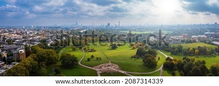 Beautiful aerial view of London with many green parks and city skyscrapers in the foreground.