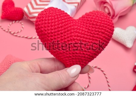 A red heart is in women's hands. Banner, Valentine's Day card. Mother's Day. Women's hands hold a knitted heart in their palms. A holiday card. Copy space. Flat lay, top view.