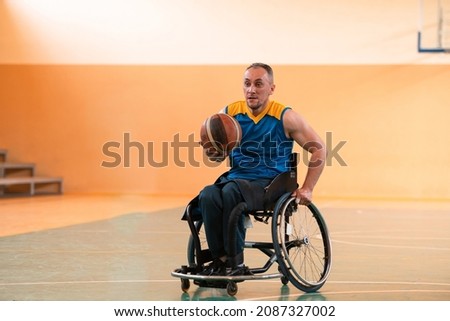 A photo of person with a disability playing basketball in a modern sports arena. The concept of sport for people with disabilities